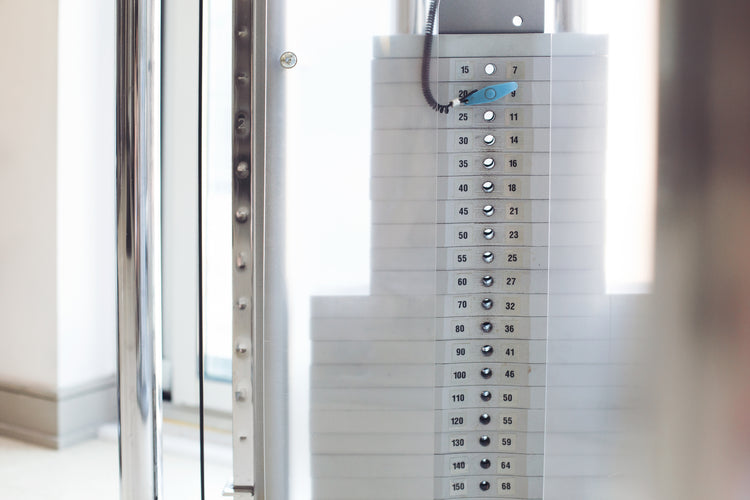 Close-up van een gewichtsstapelmachine in een sportschool met selecteerbare gewichten van 5 tot 150 kilogram.