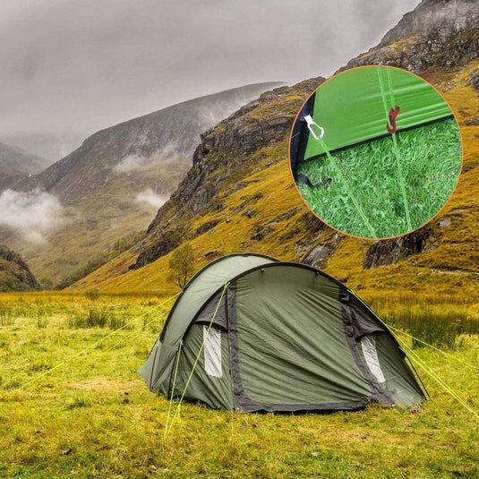 Een groene tent staat op een grasveld met daarachter mistige heuvels. Een inzet benadrukt de stevige aluminium nylon scheerlijnbevestiging van de tent: Laat je tent stevig staan met onze reflecterende scheerlijn touwen! Ideaal voor kampeeravonturen.