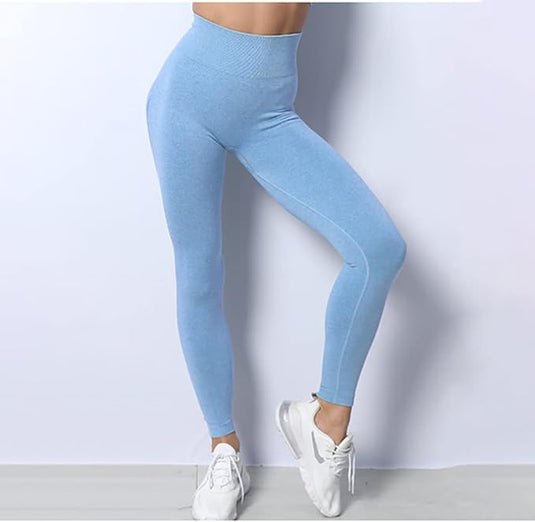 In een blauwe legging met hoge taille en witte sneakers staat een persoon tegen een smetteloos witte achtergrond, klaar in hun "Zie er geweldig uit en voel je geweldig in deze 3-delige yoga workoutset!.