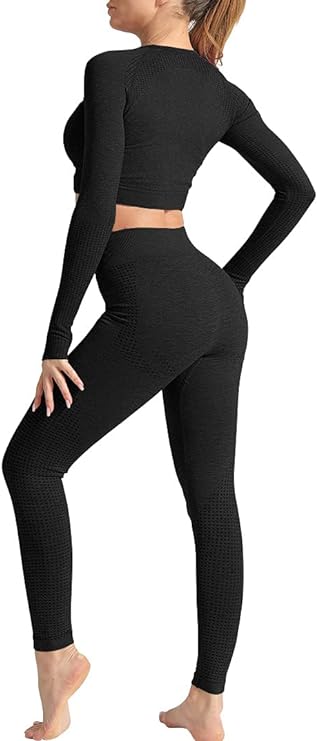 Een persoon staat op blote voeten, met het gezicht van de andere kant af, en draagt een zwarte, versleten stoffen crop top met lange mouwen en een legging met hoge taille uit de 3-delige yoga-work-outset.