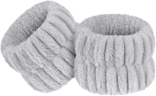 Een set van twee grijze, geribbelde, donzige polsbandjes gemaakt van zacht microvezelmateriaal, voor comfort en duurzaamheid.