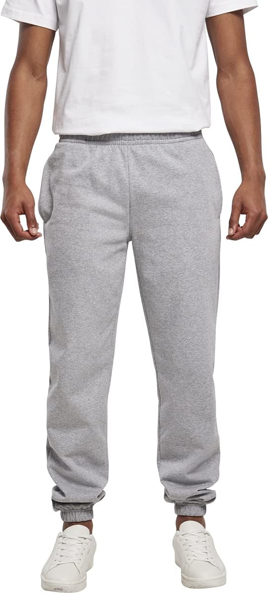 Laad afbeelding in Galerijviewer, Een persoon die een wit overhemd draagt, de &quot;Comfort, stijl en bewegingsvrijheid - De ultieme basic joggingbroek&quot;, en witte sneakers staat tegen een effen achtergrond en straalt comfort uit met hun casual ontwerp.
