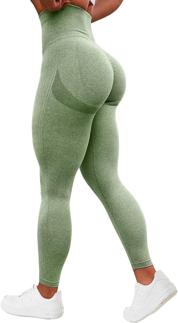 Load image into Gallery viewer, Gekleed in een groene &quot;Ervaar ultiem comfort en stijl met onze compressie sportlegging&quot; met hoge taille, een geplooid billenontwerp en witte sneakers, staat een persoon met de rug naar de camera.
