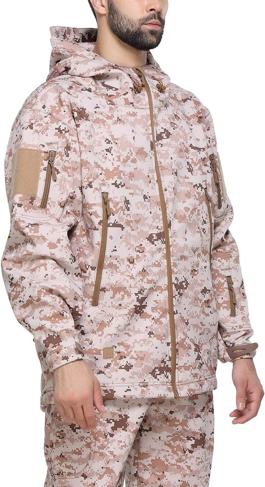 Een persoon staat tegen een effen achtergrond en draagt een jas met capuchon en een broek met een digitaal camouflagepatroon dat lijkt op de Camouflage tactische heren softshell jas voor extra comfort.