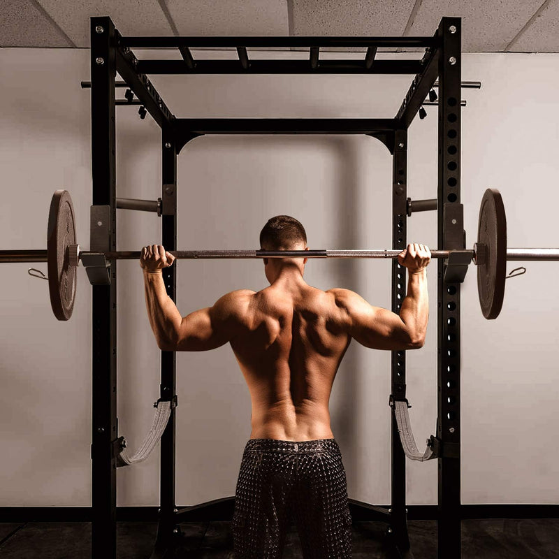 Laad afbeelding in Galerijviewer, In een sportschool tilt een gespierd persoon een halter op zijn schouders in de veilige greep van een powerrack J-haken, geheel gemaakt van hoogwaardig staal, met het gezicht van de camera af.
