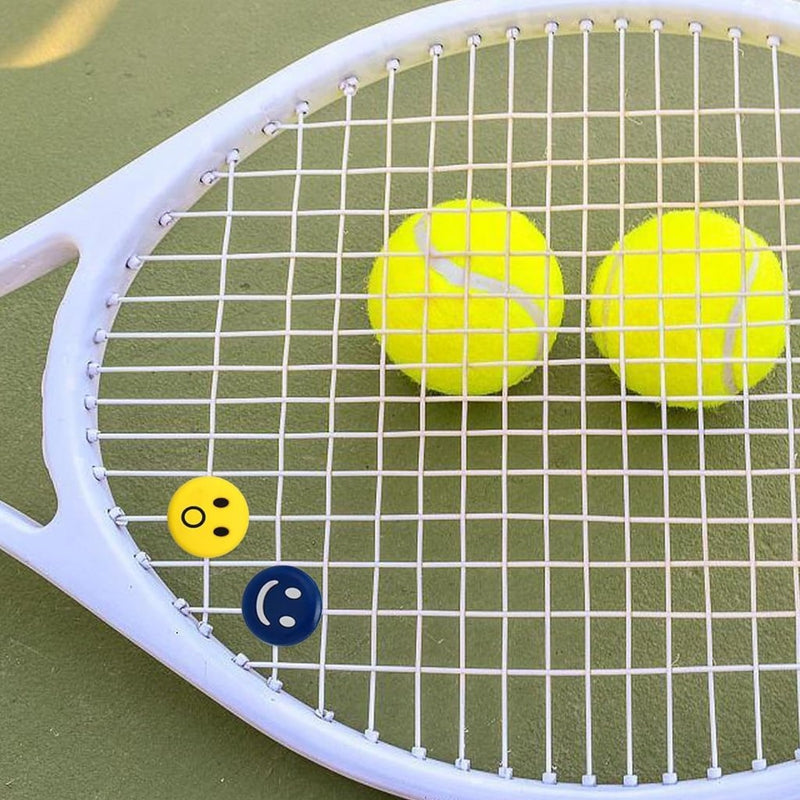 Laad afbeelding in Galerijviewer, Op de groene baan staat een tennisracket met twee gele ballen aan de snaren met speelse emoji-stickers: verrast en knipogend. Het siliconenontwerp van &quot;Verbeter jouw spel met onze grappige tennisdempers!&quot; biedt uitzonderlijke schokdemping voor verbeterde spelprestaties.
