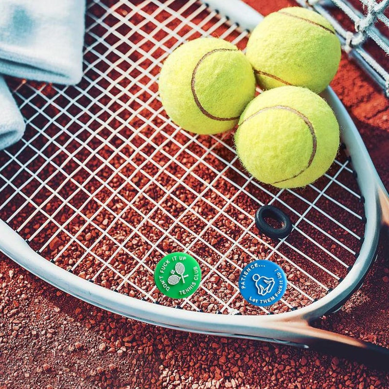 Laad afbeelding in Galerijviewer, Op een gravelbaan ligt een tennisracket met drie groene ballen naast een handdoek en twee ronde tags met tekst en iconen. Verbeter uw spel met ons product: &quot;Verbeter uw spel met onze grappige tennisdempers!&quot; dat superieure schokdemping biedt voor elke wedstrijd.
