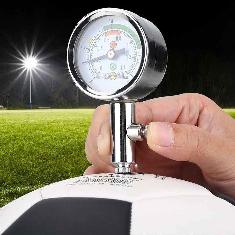 Load image into Gallery viewer, Met de &quot;Optimaliseer je spel met onze mini luchtdrukmeter voor sportballen!&quot; controleert een hand &#39;s nachts de luchtdruk van een zwart-witte voetbal op het veld, om er zeker van te zijn dat de bal klaar is om mee te spelen.

