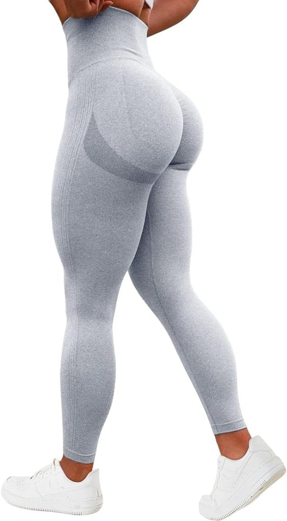 Load image into Gallery viewer, Een persoon in een grijze legging met hoge taille, een geplooid billenontwerp en witte sneakers, van achteren gezien, draagt de Ervaar ultiem comfort en stijl met onze compressie sportlegging!.
