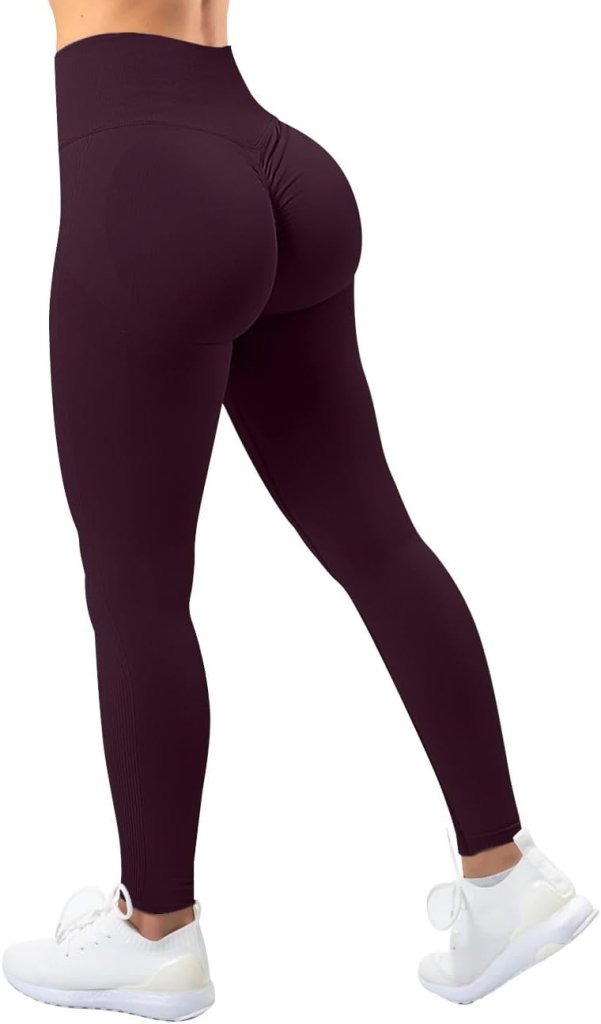 Load image into Gallery viewer, Het individu staat zelfverzekerd, gekleed in de Ervaar ultiem comfort en stijl met onze compressie sportlegging in zwart met hoge taille, een geplooid billenontwerp en frisse witte sneakers, één been naar voren gericht.
