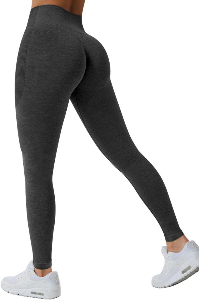 Load image into Gallery viewer, De persoon, in de compressie sportlegging met een geplooide billenontwerp en een hoog getailleerde stijl, staat met één been naar voren in witte sneakers tegen een eenvoudige witte achtergrond.
