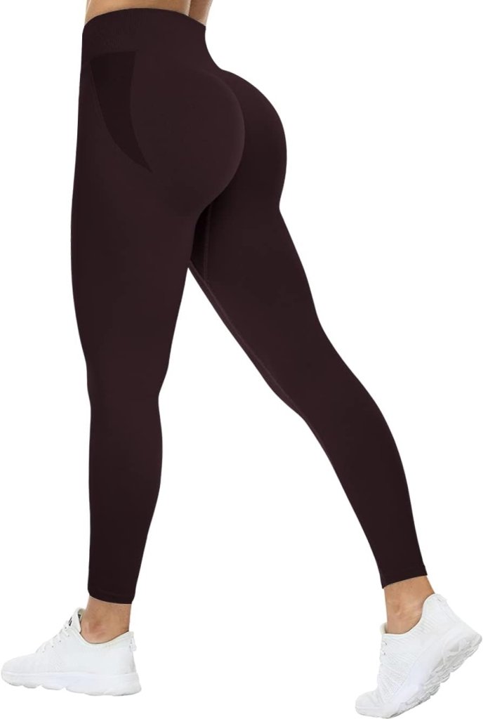 Load image into Gallery viewer, Gekleed in de &quot;Ervaar ultiem comfort en stijl met onze compressie sportlegging&quot; met een geplooid billenontwerp en witte sneakers, staat de persoon zijwaarts met het rechterbeen licht gebogen, tegen een effen witte achtergrond.
