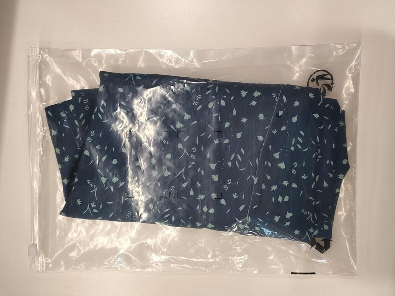 Laad afbeelding in Galerijviewer, De Sportieve en stijlvolle golfskort voor dames, in een chique blauw patroon, zit netjes opgevouwen in een doorzichtige plastic tas met een strakke zwarte ritssluiting.
