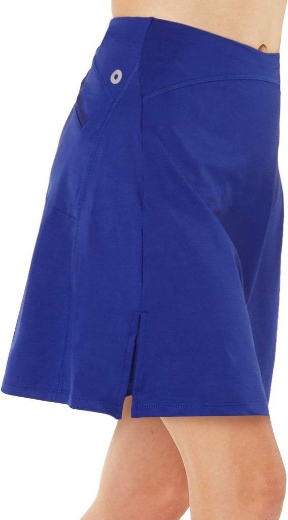 Laad afbeelding in Galerijviewer, Zijaanzicht van een persoon die de Sportieve en stijlvolle golfskort voor dames draagt in knielang koningsblauw met een zijsplit, vervaardigd uit geweven materiaal voor ultiem comfort.
