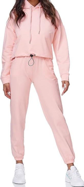 Laad afbeelding in Galerijviewer, Een persoon die het Dames joggingpak: Comfort en stijl in één draagt in lichtroze, gecombineerd met witte sneakers.

