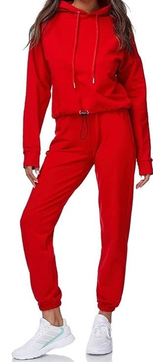 Laad afbeelding in Galerijviewer, Iemand draagt het &quot;Dames joggingpak: Comfort en stijl in één&quot;, een rode hoodie en een joggingbroek van hoogwaardige materialen, gecombineerd met witte sneakers, en staat tegen een effen witte achtergrond.
