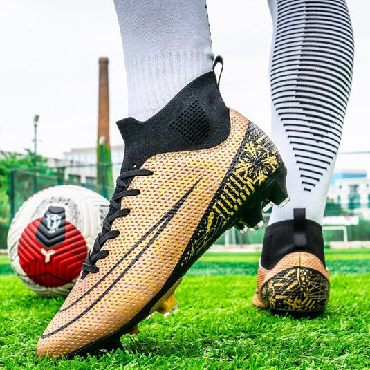 Een persoon die "Domineer het veld met deze hoogwaardige voetbalschoenen draagt!" in goud en witte sokken staat op het gras naast een voetbal, wat hun grip en stabiliteit benadrukt.