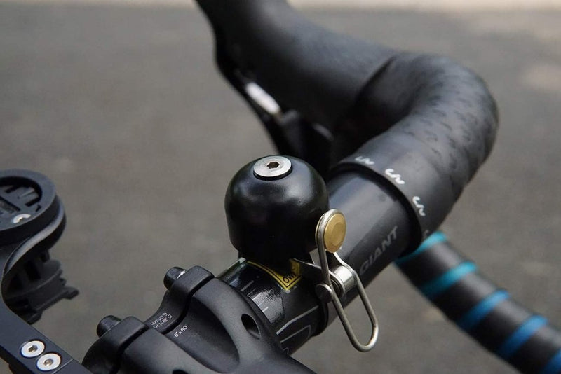 Load image into Gallery viewer, Stuur met &quot;Stijlvol, luid en officieel – De perfecte retro fietsbel voor jouw rit!&quot; en een GPS-houder tegen een onscherpe wegachtergrond.
