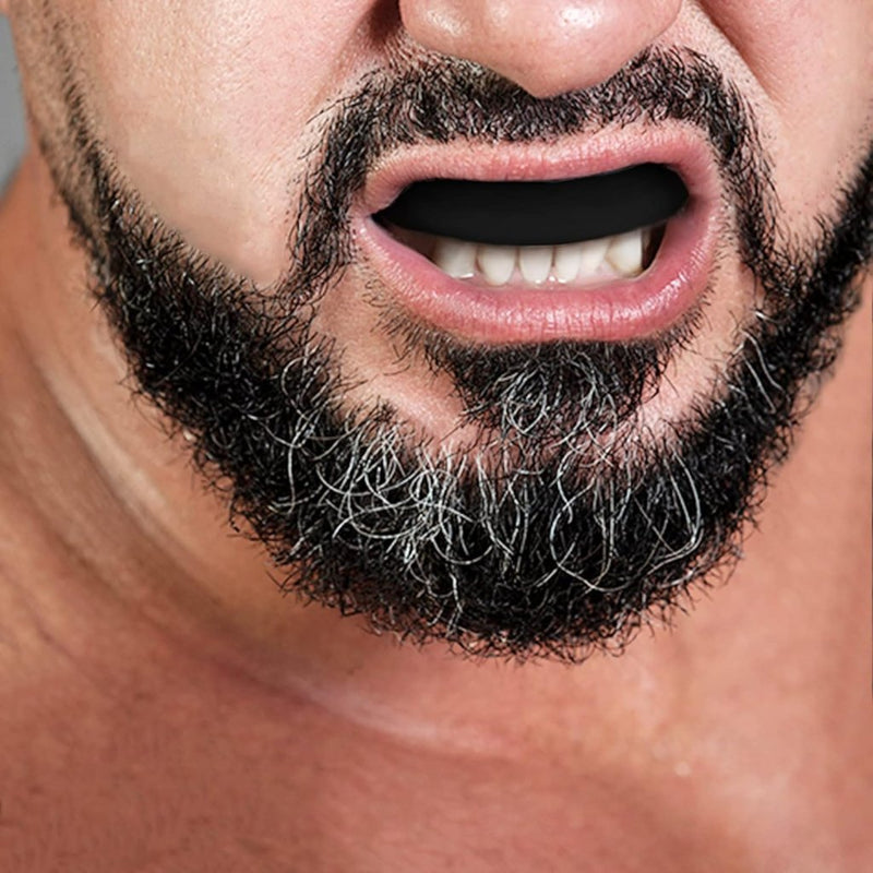 Laad afbeelding in Galerijviewer, Een close-up van iemand met een dikke, grijzende baard en open mond alsof hij klaar is voor actie in de vechtsport: bescherm je gebit met onze gebitsbeschermers!.
