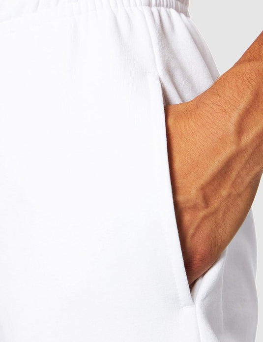 Close-up van een hand in de zak van Comfortabele en stijlvolle heren joggingbroek – Jouw dagelijkse essential, die stijl en comfort uitstraalt tegen een lichtgrijze achtergrond.