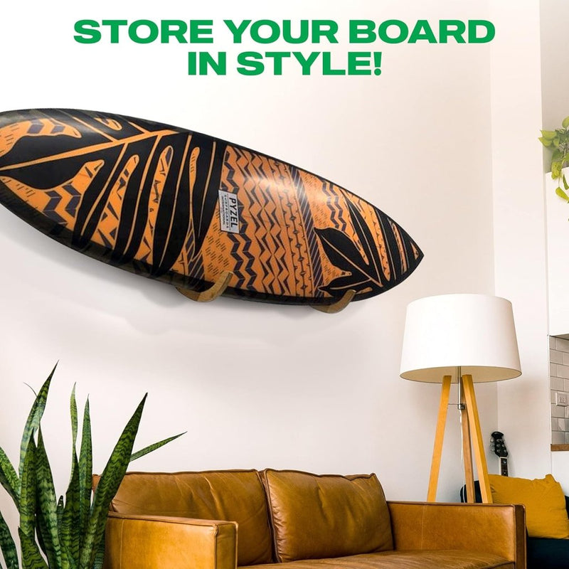 Load image into Gallery viewer, De &quot;Jouw surfplank verdient een stijlvolle display! 🏄‍♂️&quot; hangt aan een witte muur boven een bruine leren bank met een staande lamp en een hoge plant ernaast. De tekst bovenaan luidt: &quot;STORE YOUR BOARD IN STYLE!.
