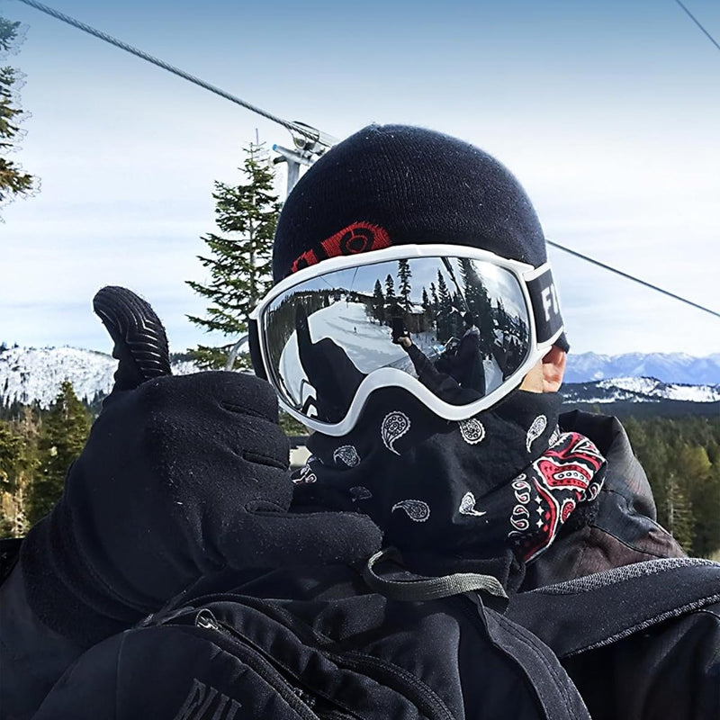 Laad afbeelding in Galerijviewer, Een persoon met een skimasker, Skibril met UV-bescherming en anti-mist coating en handschoenen steekt zijn duim omhoog op een besneeuwde berg. De dubbele anti-mist lens van de bril zorgt voor helder zicht, terwijl bomen en een heldere lucht de perfecte alpine achtergrond creëren.
