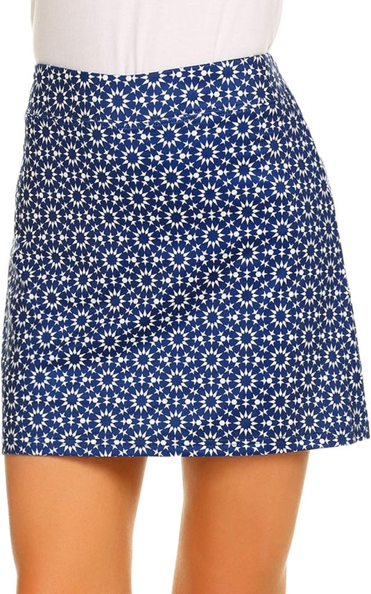 Een persoon die een blauwe rok met een wit bloemenpatroon en een witte top draagt, getoond vanaf het midden van de dij tot aan de taille, toont de elegantie van "Sportief en stijlvol – De perfecte sportrok voor elke activiteit!.