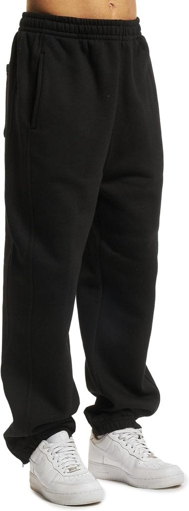 Laad afbeelding in Galerijviewer, Een persoon die een comfortabele en stijlvolle joggingbroek voor heren en witte sneakers draagt, staat tegen een effen achtergrond.
