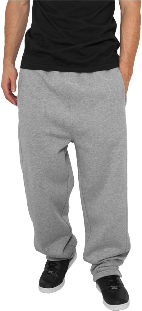 Laad afbeelding in Galerijviewer, Gekleed in een zwart shirt, een comfortabele en stijlvolle joggingbroek voor heren in grijs en zwarte sneakers, staat de persoon met de handen in de zakken tegen een effen achtergrond, wat een moeiteloze stijl uitstraalt.
