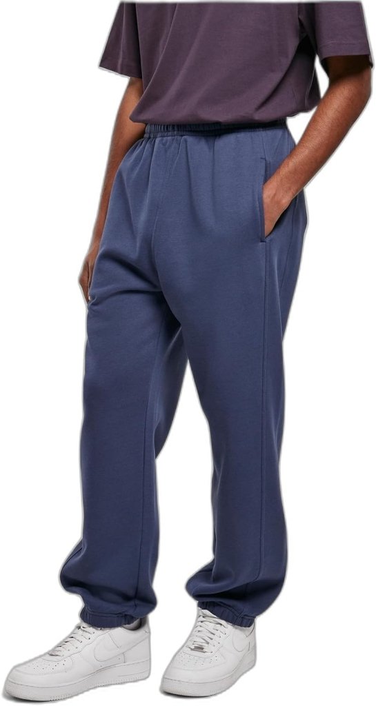 Laad afbeelding in Galerijviewer, Persoon met een donker t-shirt, comfortabele en stijlvolle joggingbroek voor heren in blauw en witte sneakers. Handen in de zakken, staande tegen een effen achtergrond met een nonchalante slanke snit.
