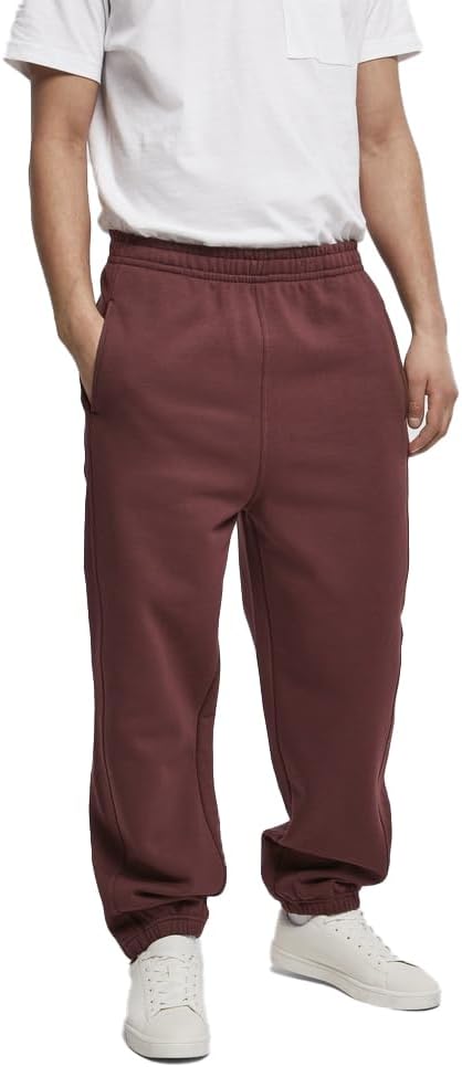 Een persoon met een wit T-shirt, een comfortabele en stijlvolle joggingbroek voor heren in het kastanjebruin met een nonchalante slanke snit, en witte sneakers. Hun handen stopten nonchalant in de zakken van de broek.