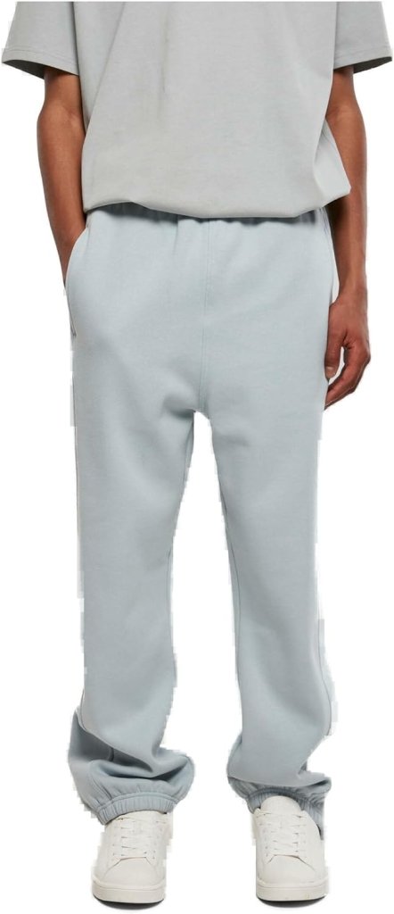 Laad afbeelding in Galerijviewer, Een persoon staat met de handen in de zakken, draagt een grijs t-shirt, een comfortabele en stijlvolle joggingbroek voor heren in lichtgrijs en witte sneakers.
