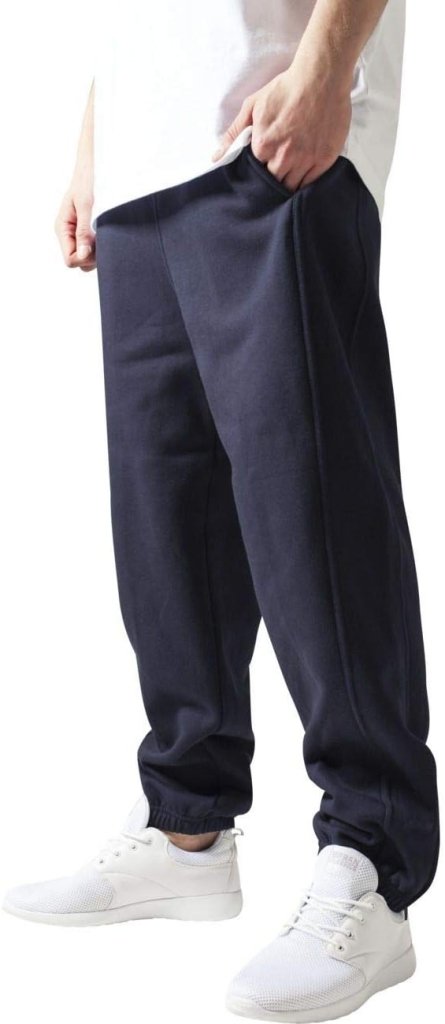 Laad afbeelding in Galerijviewer, Een persoon draagt een comfortabele, stijlvolle herenjoggingbroek in het zwart, gecombineerd met witte sneakers en een vleugje wit overhemd.
