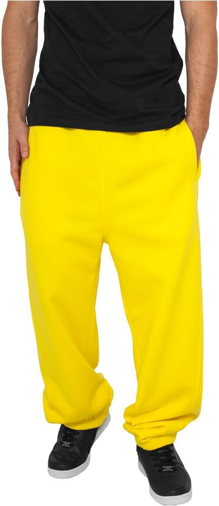 Laad afbeelding in Galerijviewer, Een persoon staat nonchalant met de handen in de zakken, gekleed in een comfortabele en stijlvolle joggingbroek voor heren in felgeel, gecombineerd met een zwart shirt. Dit zorgt voor een nonchalante, slanke pasvorm en een ontspannen, maar toch gestroomlijnde look.
