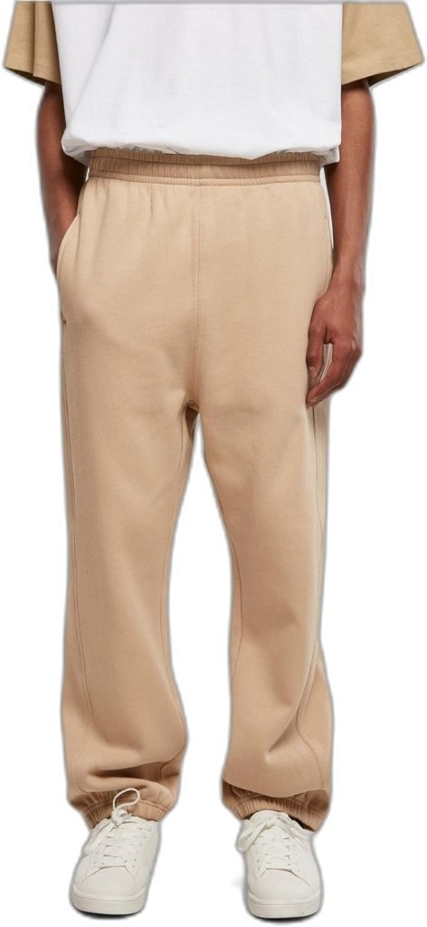 Laad afbeelding in Galerijviewer, Een persoon draagt een Comfortabele en stijlvolle joggingbroek voor heren, een wit T-shirt en witte sneakers terwijl hij tegen een effen achtergrond staat.
