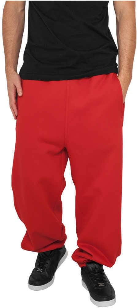 Laad afbeelding in Galerijviewer, Een man in een zwart overhemd en rode &quot;Comfortabele en stijlvolle joggingbroek voor heren&quot;, gecombineerd met zwarte sneakers, staat met zijn handen in zijn zakken tegen een effen achtergrond.
