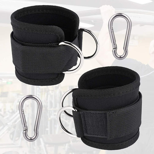 Tegen de achtergrond van een sportschool worden twee zwarte neopreen enkelbanden met metalen D-ringen en karabijnhaken getoond, ideaal voor trainingen met kabelmachines. Dit product staat bekend als 
