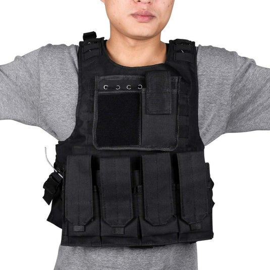 Een persoon draagt "Ontketen je ware potentieel met het verstelbare tactische vest voor paintball!" - een zwart tactisch vest met meerdere zakken - over een grijs shirt. Het is verstelbaar voor comfort en veiligheid in scenario's boordevol actie.