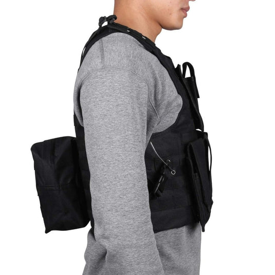 Een persoon draagt een tactisch zwart vest "Ontketen je ware potentieel", ontworpen met meerdere zakken en een zijvak, over een grijs shirt met lange mouwen. Het zijprofiel benadrukt het verstelbare ontwerp voor comfort en flexibiliteit, waardoor het perfect is voor paintball.