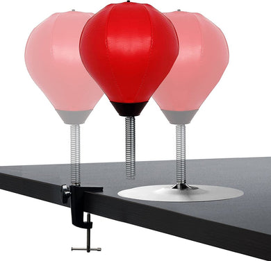 Drie veelzijdige Ontdek stressvermindering boksballen - twee rood, één gedeeltelijk transparant - zijn perfect om stress te verminderen. Vastgeklemd aan een donker tafelblad, helpen ze de hand-oogcoördinatie te verbeteren.