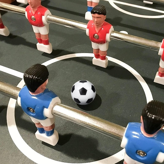 Close-up van een tafelvoetbalspel met rode en blauwe ABS-kunststoffiguren met de hoogwaardige tafelvoetbalballetjes op het veld. Speelplezier gegarandeerd!.