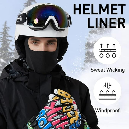 Een persoon met een helm en bril draagt een zwarte gezichtsbedekking en kleurrijke handschoenen met het label "WICKED" in een besneeuwde omgeving, perfect voor buitenactiviteiten. De helmvoering, bekend als "Blijf warm en comfortabel in de kou met deze bivakmuts," heeft zweetafvoerende en winddichte eigenschappen.