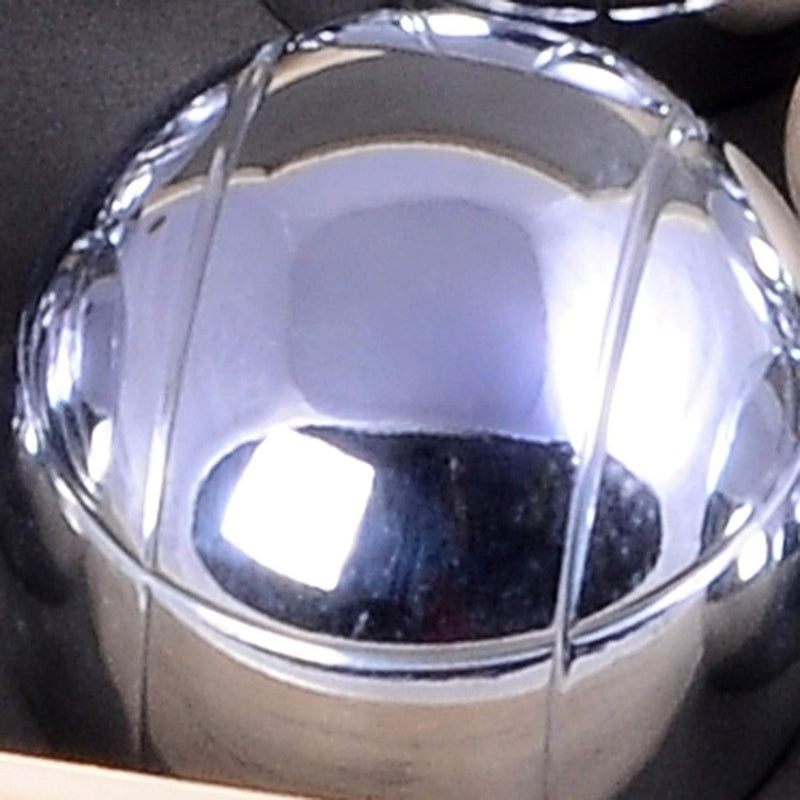 Laad afbeelding in Galerijviewer, Een close-up van een glanzende metalen bol met groeven, vergelijkbaar met de petanquebal uit &quot;Geniet van eindeloos plezier met ons petanquespel in houten kist&quot;, die het licht prachtig reflecteert tegen een donkere achtergrond - een perfect luxe cadeau-idee.
