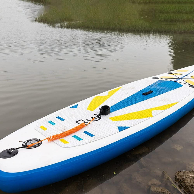Laad afbeelding in Galerijviewer, Een blauw, wit en geel opblaasbaar paddleboard met een oranje koord drijft vredig boven het grasachtige water, met de Coiled SUP-riem: de veiligste manier om van het water te genieten voor een veilige en comfortabele ervaring.
