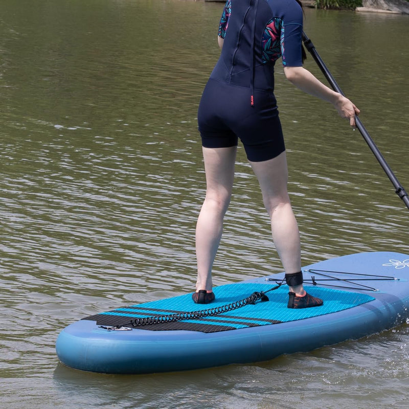 Laad afbeelding in Galerijviewer, Een persoon die op kalm water paddleboardt, een wetsuit en een Coiled SUP-lijn draagt: de veiligste manier om van het water te genieten.
