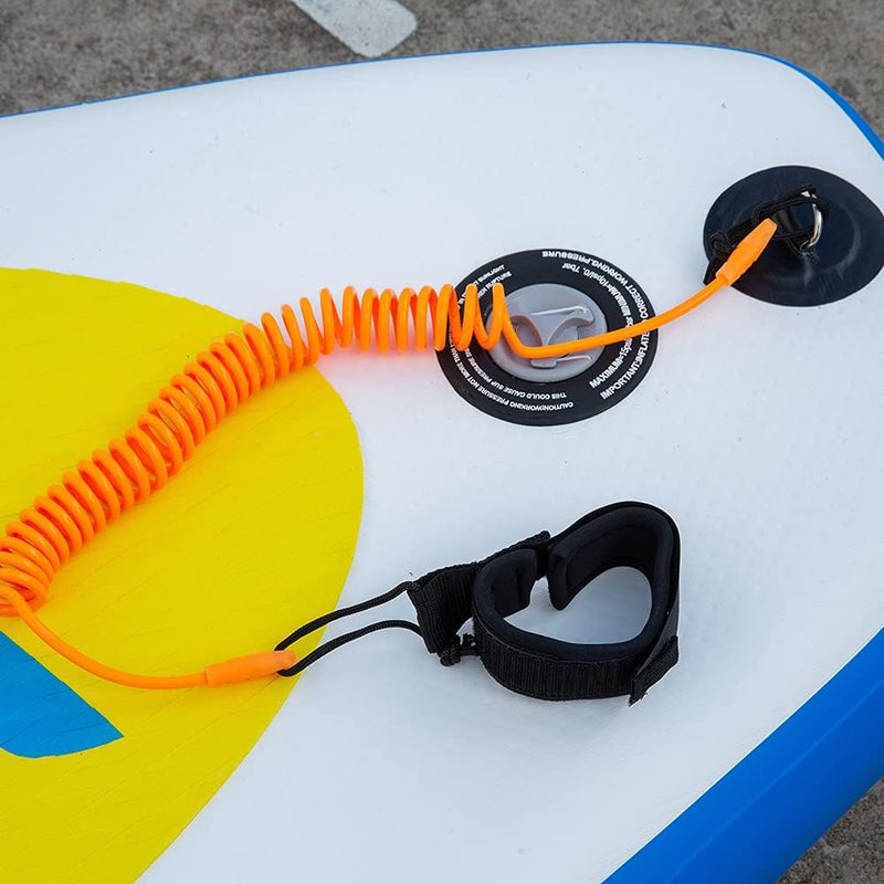 Laad afbeelding in Galerijviewer, De &quot;Coiled SUP leash: de veiligste manier om te genieten van het water&quot;, vastgemaakt aan een opblaasbaar paddleboard, zorgt voor veiligheid en comfort met zijn zwarte enkelband die veilig op een betonnen oppervlak rust.
