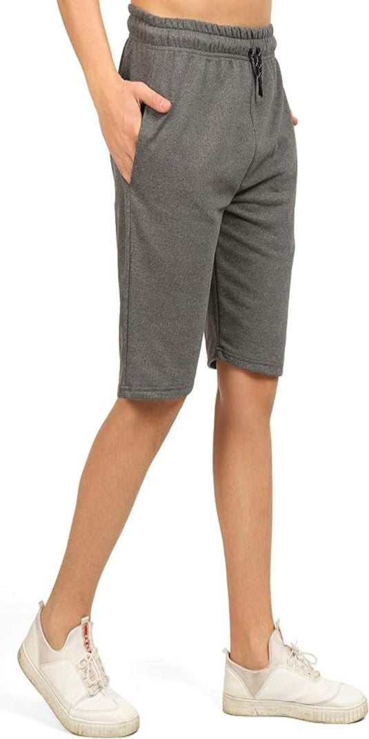Een persoon in een comfortabele, veelzijdige bermuda en witte sneakers staat met een hand in de zak.