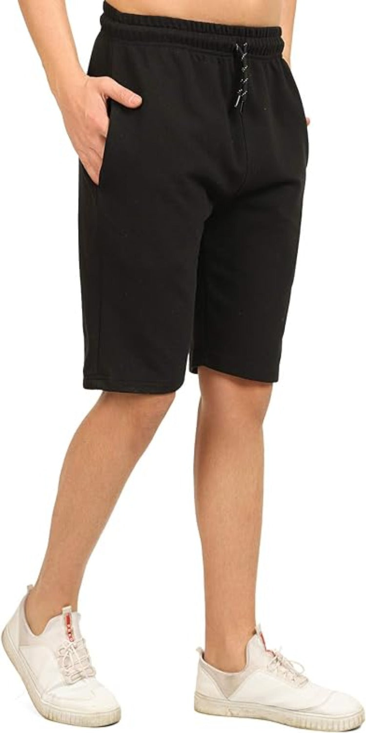 Laad afbeelding in Galerijviewer, Een persoon draagt de comfortabele, veelzijdige bermudashorts in zwart-witte sneakers met één hand in de zak en staat tegen een witte achtergrond.
