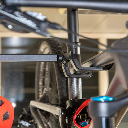 Close-up van een fiets die met een frameklem op een autodrager is bevestigd. Er hangt een rode helm naast, wat de nadruk legt op het "Optimaliseer je ruimte met onze stijlvolle fiets ophangsysteem" voor degenen die waarde hechten aan ruimtebesparende oplossingen.