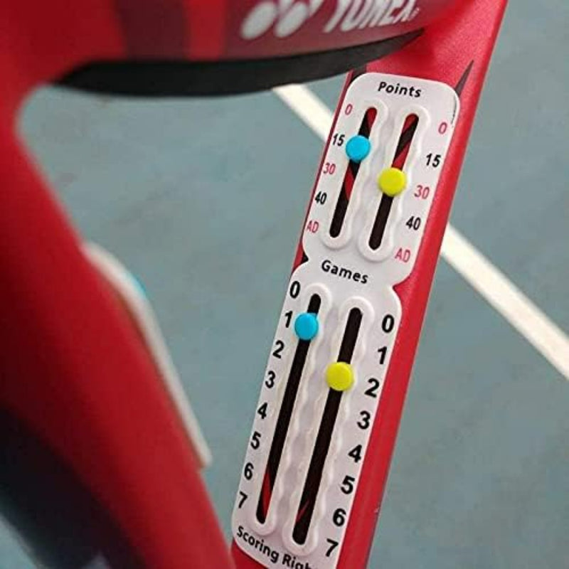 Load image into Gallery viewer, Close-up van een Draagbaar tennis scorebord op een rood racket, met punten en spellen met gekleurde pinnen op genummerde tracks. De baanlijnen zijn zichtbaar op de achtergrond, wat de compatibiliteit met elk universeel montagesysteem laat zien.
